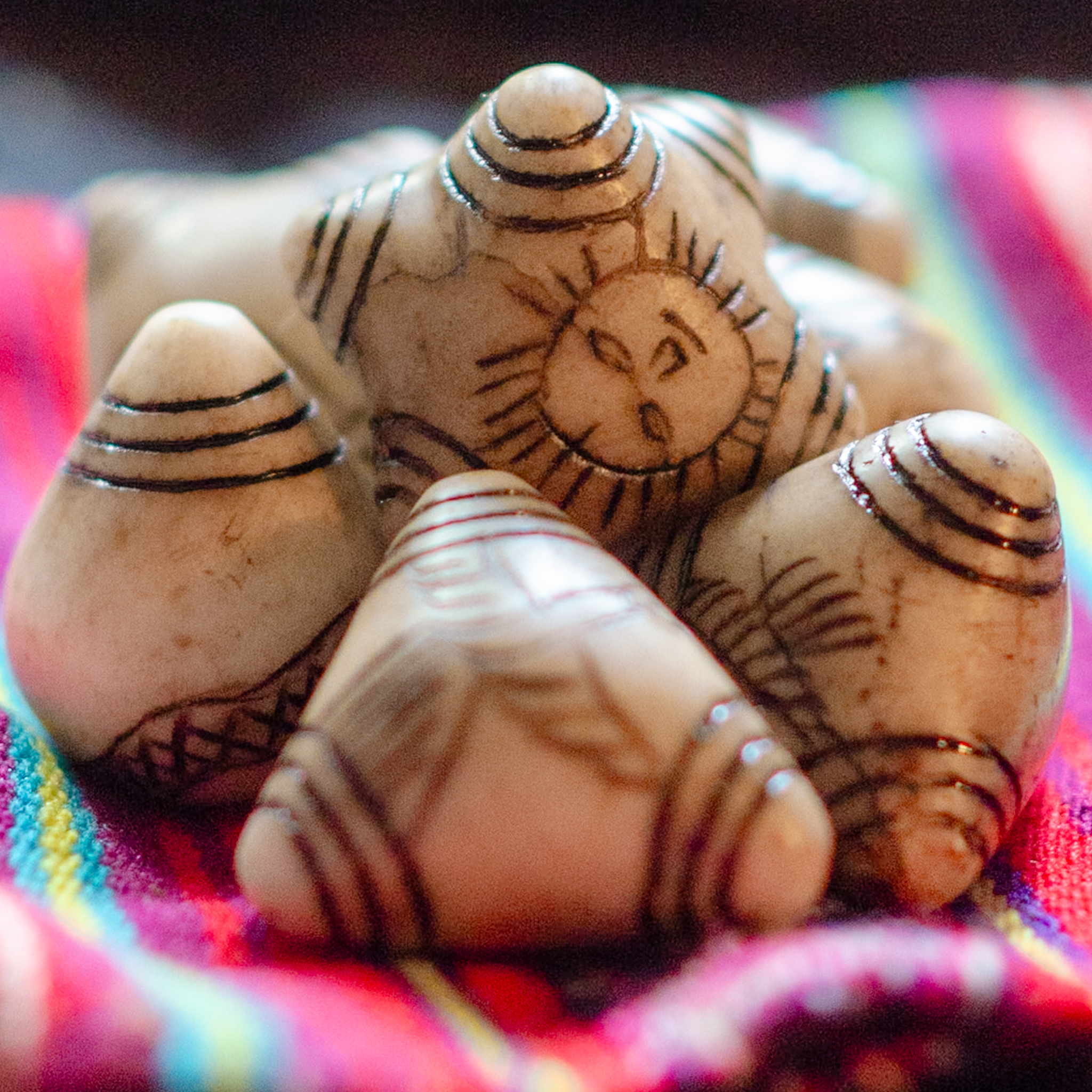 Four Chumpis Stones are sitting on a multicolored cloth.