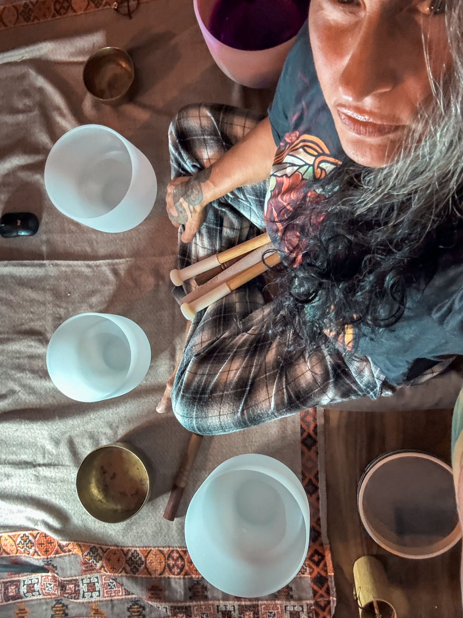 A selfie of Athena sitting on the floor amongst crystal and Tibetan singing bowls