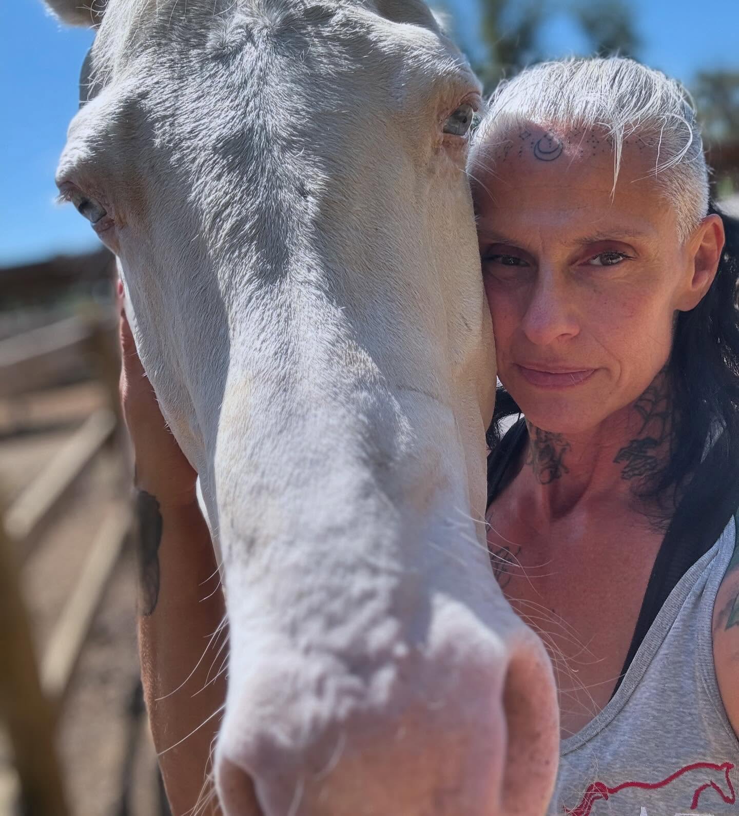 Athena is cradling a white horse's head between her and and her cheek